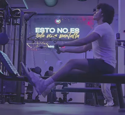 Persona entrenando en un gimnasio frente a un vidrio con el logo de 99 Degrees y el texto «Esto no es solo una pantalla»