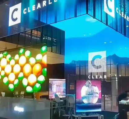 Stand de exposición con pantallas LED que muestran frutas y un cielo azul