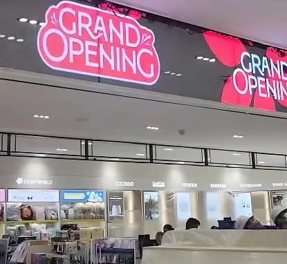 Pantallas LED rojas con un anuncio de inauguración sobre locales de un centro comercial